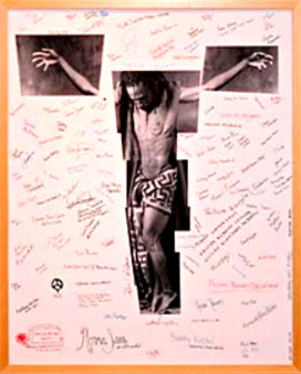 Signed Artwork Display
Framed mixed-media artwork featuring a black-and-white photographic figure with outstretched arms and patterned shorts, surrounded by handwritten signatures and notes in red and black ink on a light background. The piece appears commemorative or collaborative in nature and is displayed within a simple wood frame.