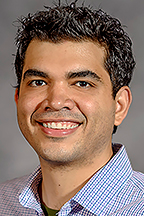 Portrait of MTSU illustration professor Tony Rodriguez smiling toward the camera. He wears a blue checkered button-down shirt against a neutral studio-style background.