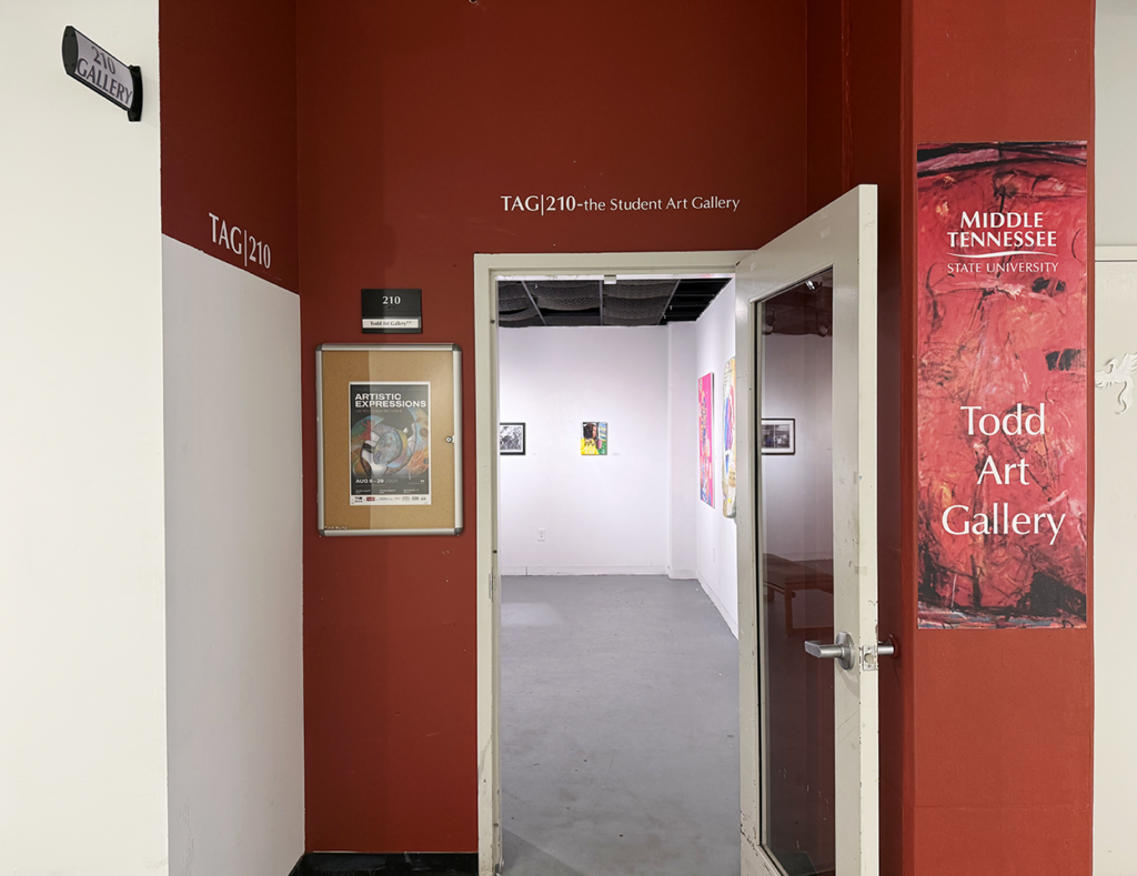 Entrance to TAG 210, the Student Art Gallery at Middle Tennessee State University, with red walls, gallery signage, an exhibition poster, and an open door revealing artworks displayed inside.