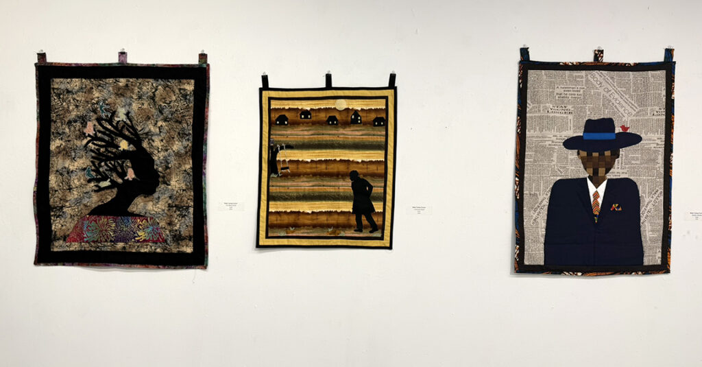 Three textile artworks displayed side by side, featuring a silhouetted figure beneath a tree, a rural landscape with figures, and a suited figure against a newspaper-text background.