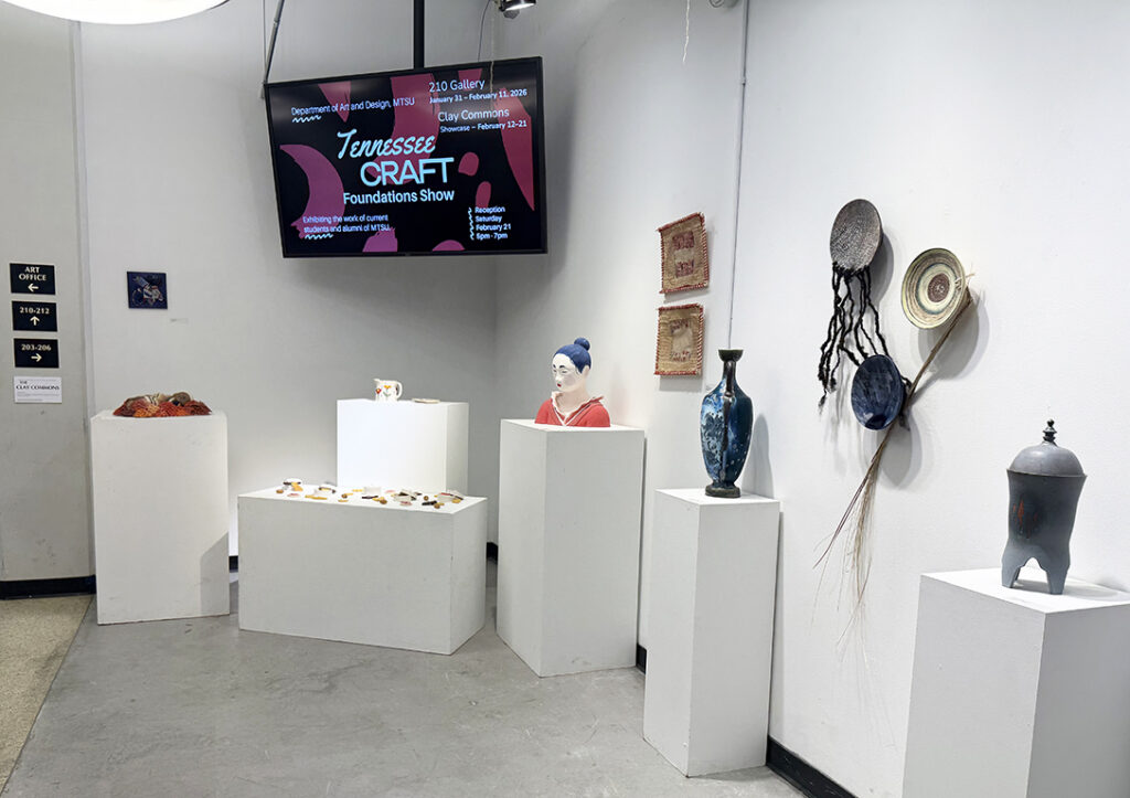 View of the Tennessee Craft Foundations Show in Clay Commons, with ceramics, textiles, and mixed media works displayed on white pedestals and walls.
