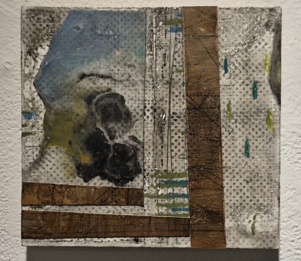 Confined: Abstract mixed-media artwork with layered paper, wood-like brown strips, grid patterns, and a shadowy, curled organic form in muted blue, black, green, and white.