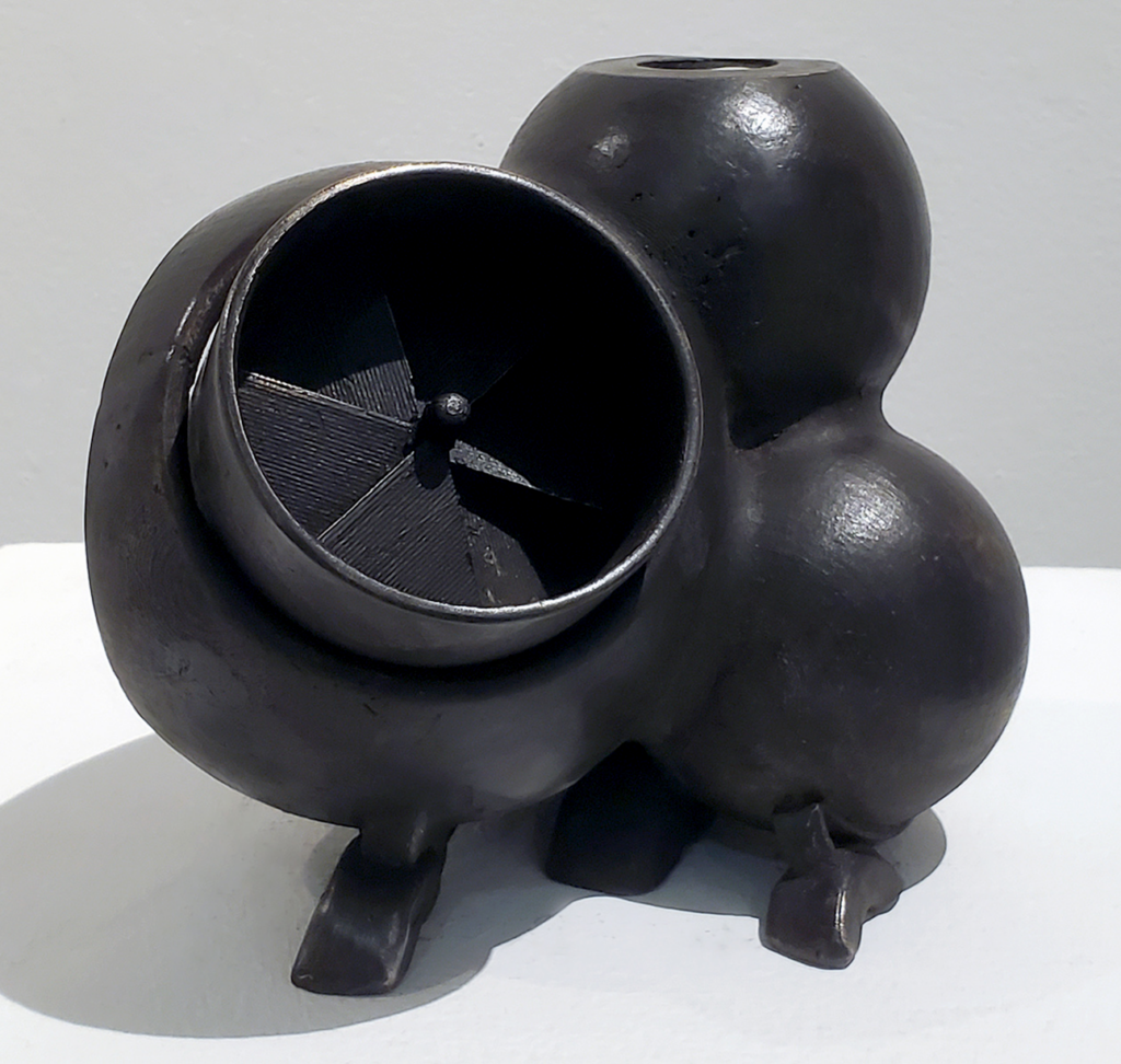 Patrick D. Wilson, Quantum Airbox: Glossy black sculptural vessel with clustered, bulbous forms and short feet. A large circular opening reveals a dark interior containing propeller-like blades.
